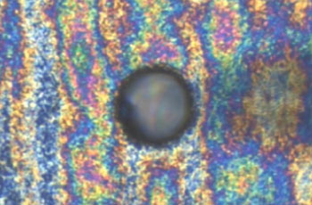 Bent tungsten probe approaching inkjet nozzle opening under polarized light microscope